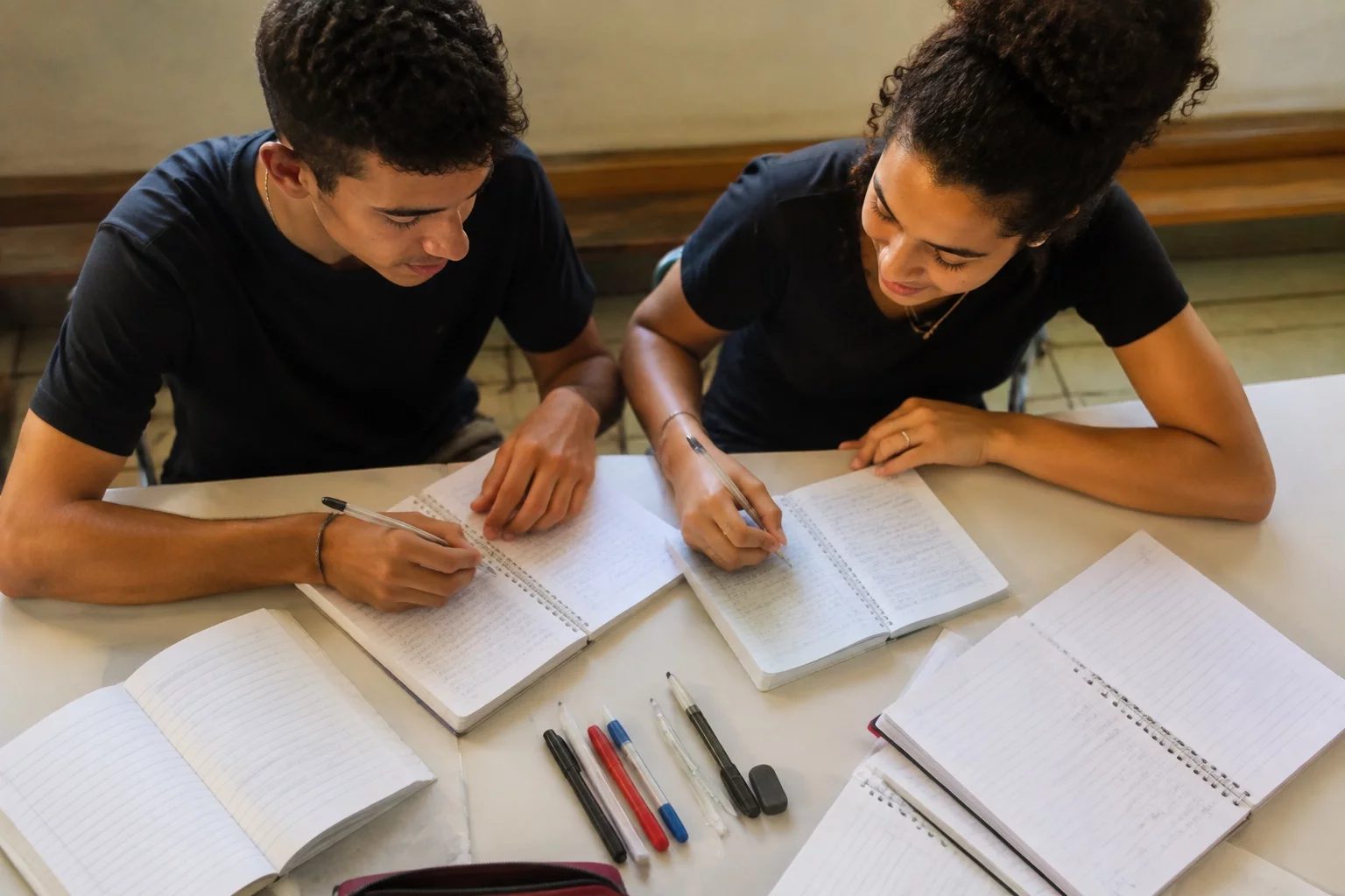 Dois estudantes preparando um debate com cadernos e marcadores