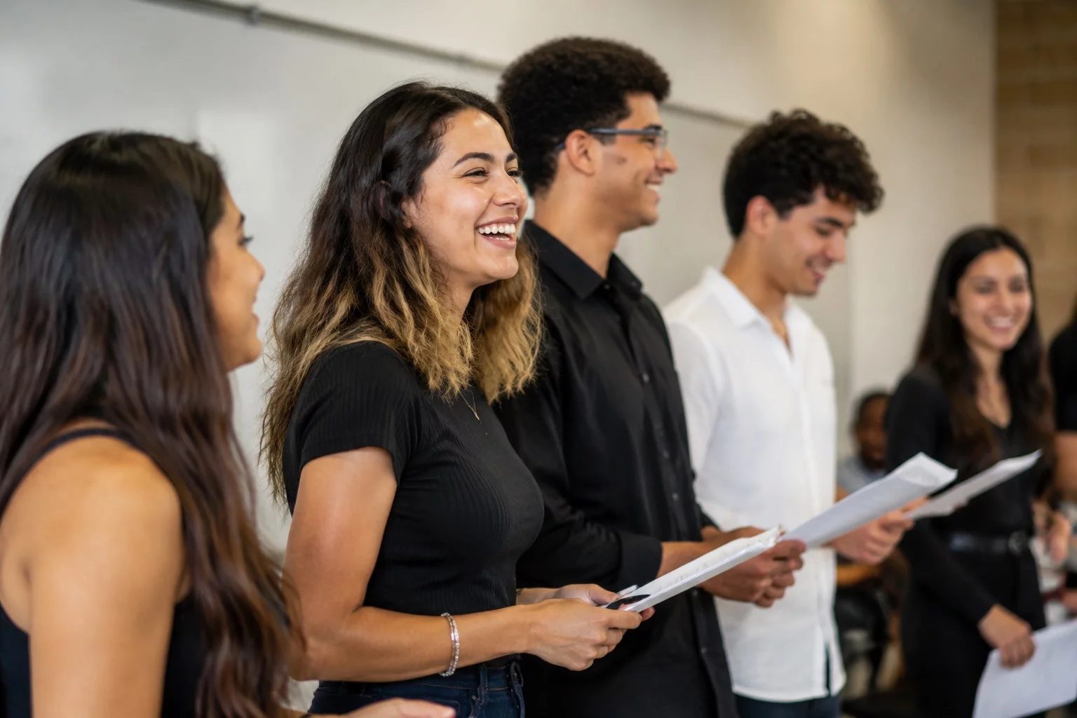 Grupo sorrindo após uma rodada de debate, com papéis nas mãos
